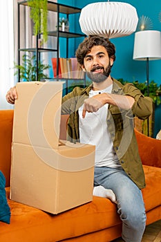 Happy arabian man shopper unpacking cardboard box delivery parcel online shopping purchase at home