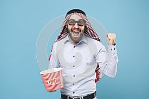Happy arabian muslim man in keffiyeh kafiya ring igal agal 3d imax glasses isolated on pastel blue background. People photo