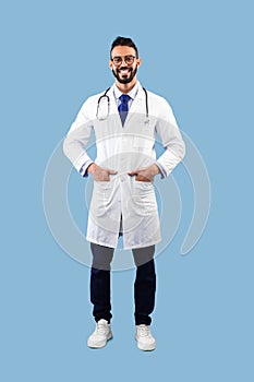 Happy Arabic Male Doctor Smiling Posing Over Blue Studio Background