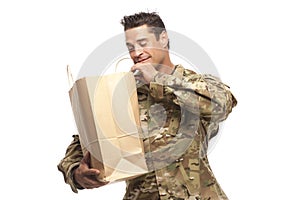 Happy army soldier looking into his shopping bag