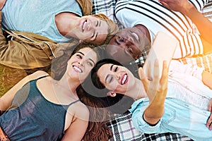 Happy as long as were together. a group of young friends taking a selfie together outdoors.