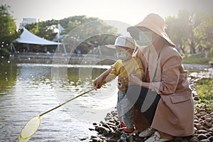 Happy Asia Chinese little boy toddler child play with his mother mom by lake holding string net catch fish carefree childhood