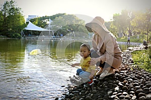 Happy Asia Chinese little boy toddler child play with his mother mom by lake holding string net catch fish carefree childhood