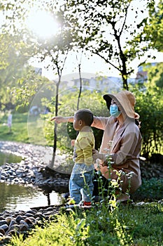 Happy Asia Chinese little boy toddler child play with his mother mom by lake holding string net catch fish carefree childhood