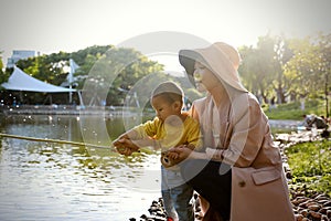 Happy Asia Chinese little boy toddler child play with his mother mom by lake holding string net catch fish carefree childhood