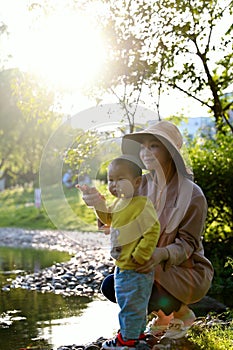 Happy Asia Chinese little boy toddler child play with his mother mom by lake holding string net catch fish carefree childhood