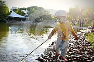 Happy Asia Chinese little boy toddler child play by lake holding string net catch fish carefree childhood parent-child activity