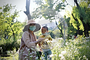 Happy Asia Chinese little boy toddler child wear mask play with his mother mom have fun hold string net catch insects childhood