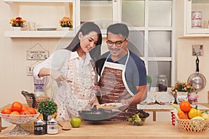 Happy asia couple cooking healthy food in their loft kitchen at home