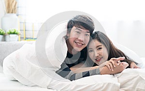 Happy Asia couple teasing each other on the bed in the bedroom.