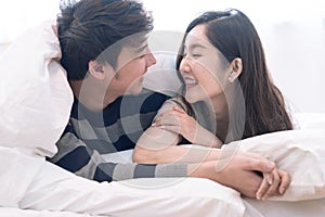 Happy Asia couple teasing each other on the bed in the bedroom.