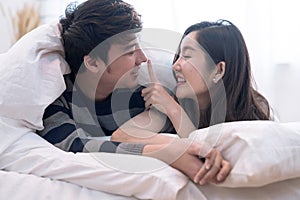 Happy Asia couple teasing each other on the bed in the bedroom.