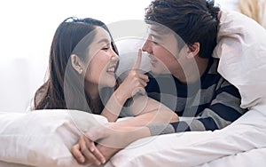 Happy Asia couple teasing each other on the bed in the bedroom.