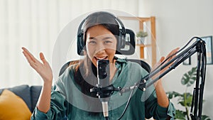 Happy asia girl record a podcast with headphones and microphone look at camera  talk and take a rest in her room. Female podcaster