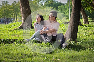 Happy asian adult man and cute child girl with love,hugging and smiling in summer nature,father and little beautiful daughter