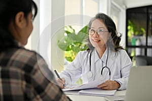 Happy Asian aged female doctor having a nice conversation with her patient in the clinic