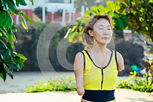 Happy asian armless woman doing meditation yoga at the tropical beach