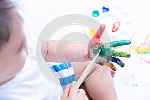 Happy asian baby child use paintbrush draw water color or fingerpaint on hand