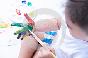Happy asian baby child use paintbrush draw water color or fingerpaint on hand photo