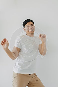 Happy asian bearded man rising his fist, happy fun unconfident dancing posing, looking at camera and standing 