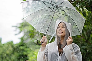 Happy Asian beautiful woman holding umbrella in raining season while standing in the park. Lifesyle Concept