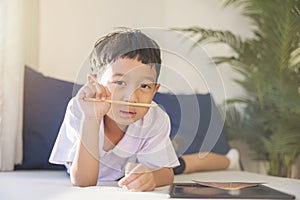 Happy Asian boy 6-7 years old, black hair, white skin, wearing white shirt and blue shorts looking at camera. Children in school