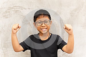 Happy Asian boy with glasses hands up and smiling over grey background.