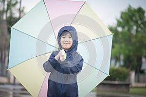 Happy asian boy holding colorful umbrella playing in the park