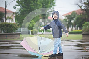 Happy asian boy holding colorful umbrella playing in the park