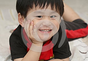 Happy asian boy lying on bed