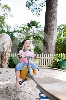 Happy asian boy playing seesaw at the playground in the park