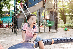 Happy asian boy playing seesaw at the playground in the park