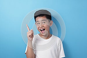 Happy Asian boy pointing finger up, having idea gesture