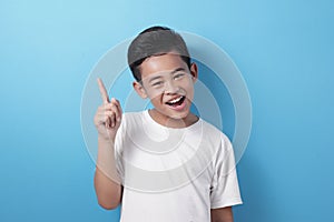 Happy Asian boy pointing finger up, having idea gesture