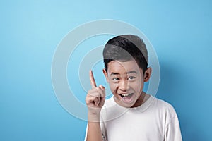 Happy Asian boy pointing finger up, having idea gesture