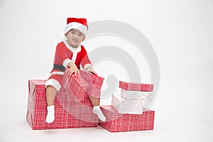 Happy asian boy with Santa Claus suit holding gift box and sitting on red gift box  on white background