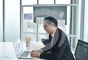 Happy Asian business man using computer laptop in office room