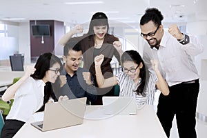 Happy asian business people looking at laptop computer