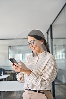 Happy Asian business woman worker using mobile phone in office, vertical.