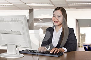 Happy asian business woman working with a desktop computer