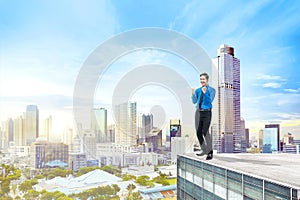 Happy asian businessman standing on the rooftop of building