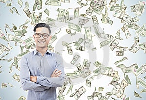 Happy Asian businessman under dollar bill rain