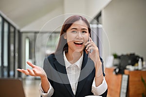 Happy asian businesswoman getting an excited news on the phone call, surprising phone call