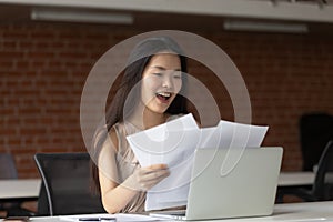Happy Asian businesswoman reading documents, receiving good news