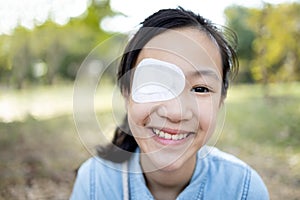 Happy asian child girl cover with blindfolded bandaged eye after surgery or treatment of strabismus,lazy eye, hygienic,prevent