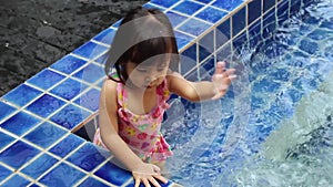 Happy Asian child girl enjoying summer vacation in swimming pool at resort.