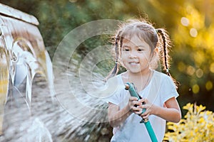 Happy asian child girl help parent washing car