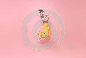 Happy Asian child girl jumping isolated on pink background