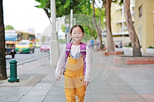 Happy Asian child girl walking with student shoulder schoolbag. Little schoolgirl with a backpack front view. Back to school