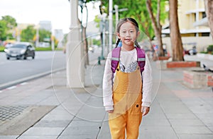 Happy Asian child girl walking with student shoulder schoolbag. Little schoolgirl with a backpack front view. Back to school